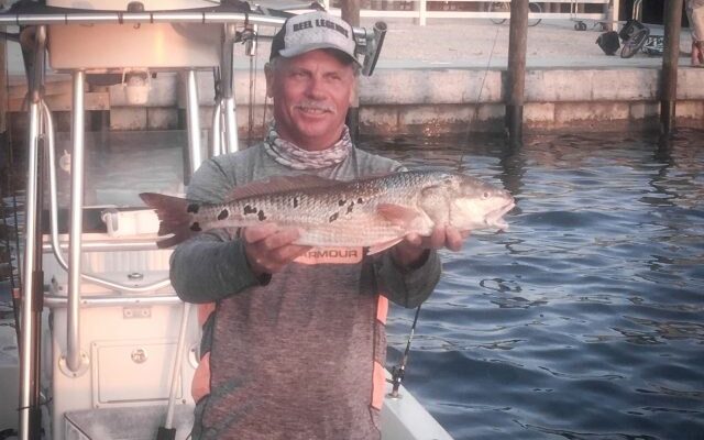 A Fishin' Mission captain holding a grouper at the marina