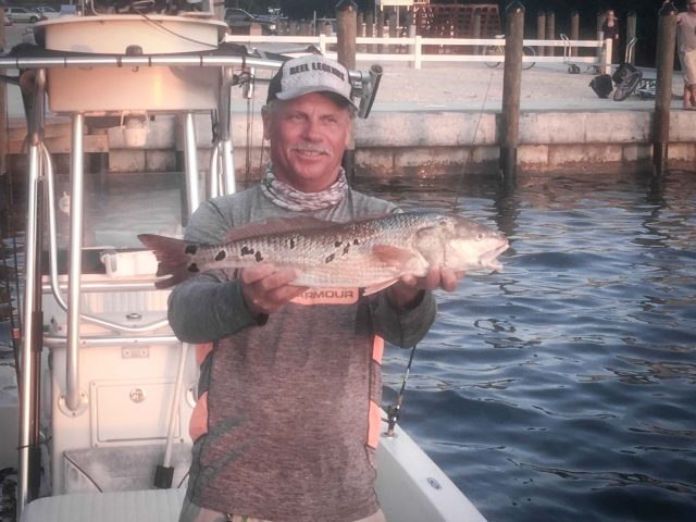 A Fishin' Mission captain holding a grouper at the marina