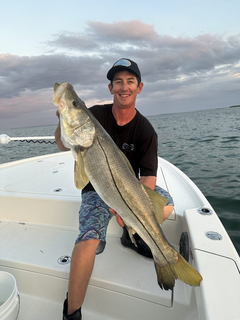 Addicted Outdoors angler holding a snook aboard a boat