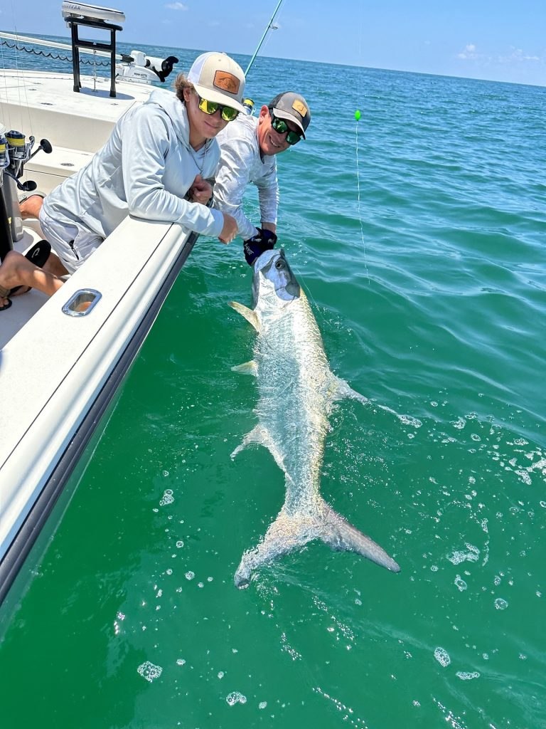Addicted Outdoors angler holding a tarpon in the water