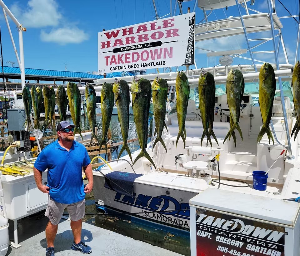 Angler beside a display of mahi mahi at the Takedown Charters dock