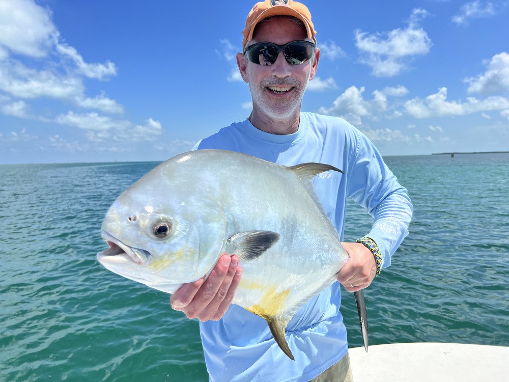 Angler displaying a permit aboard Skins and Fins Charters