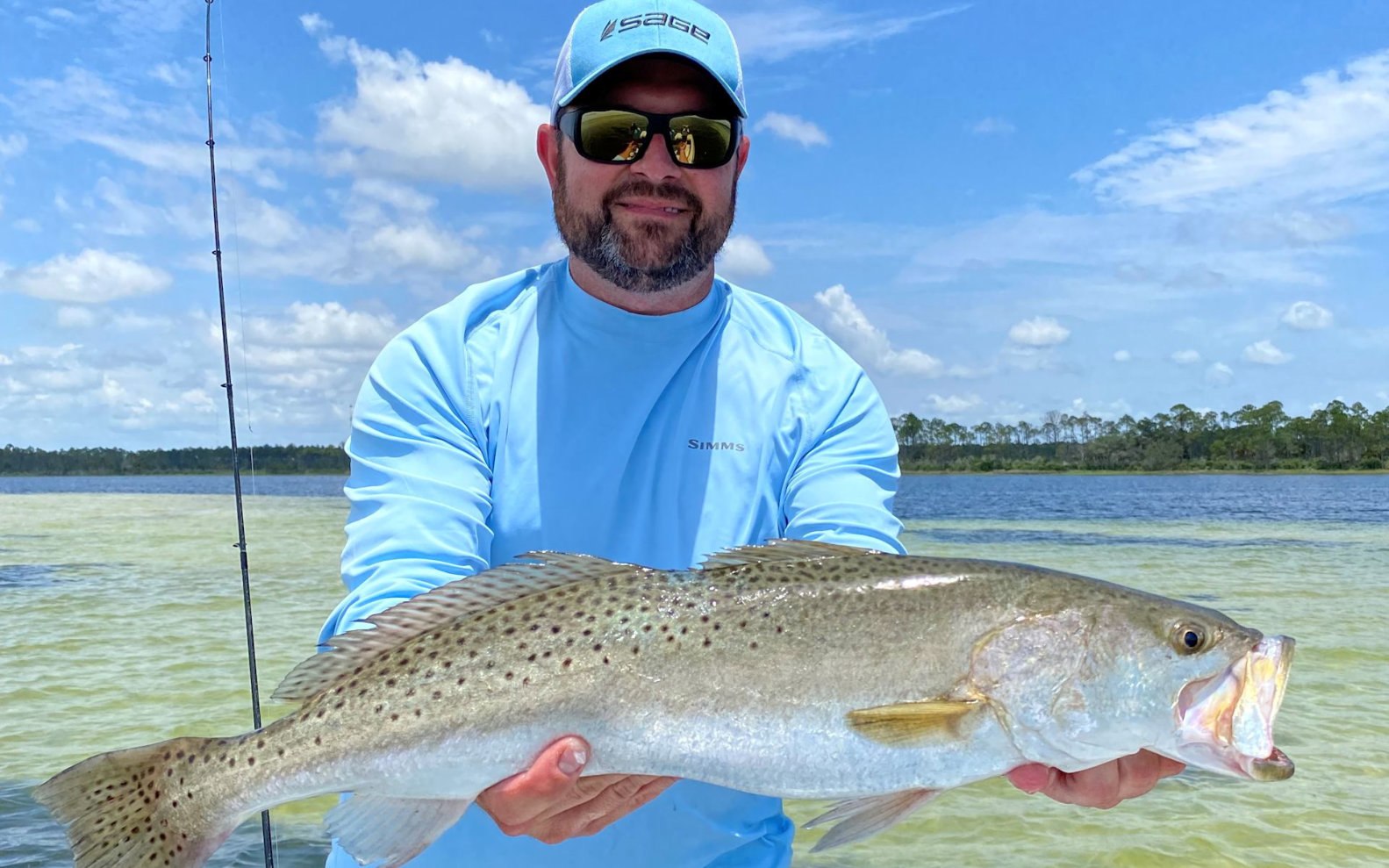Angler displaying a redfish over clear shallow water on a Robinson Brothers trip