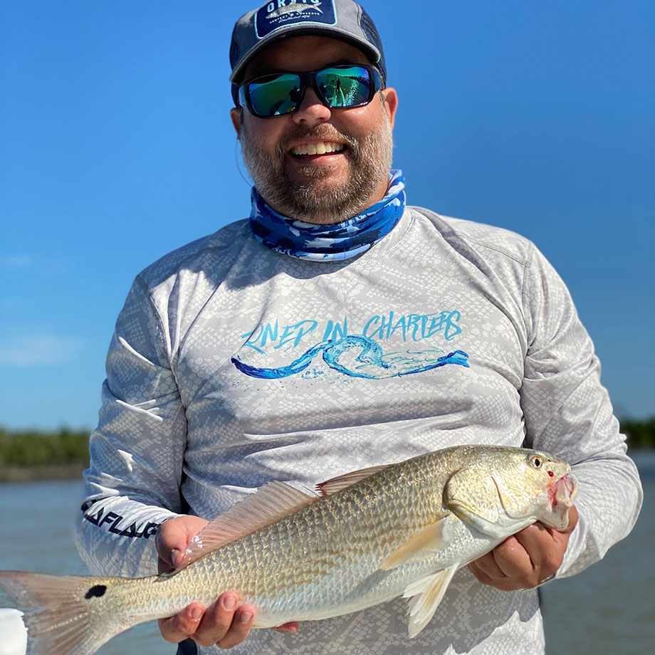 Angler holding a redfish aboard Zoned In Charters