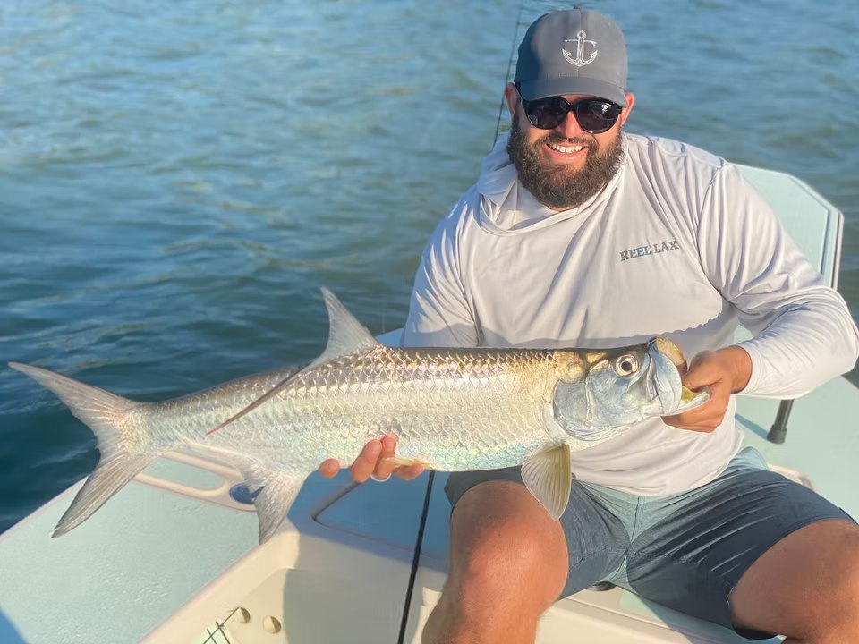 Angler holding a tarpon aboard First Class Sportfishing