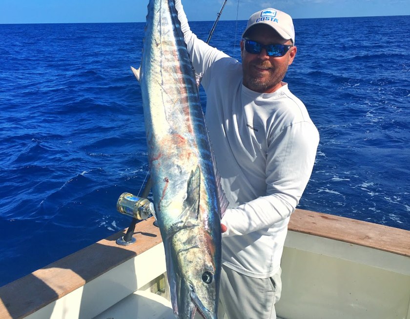 Angler holding a wahoo aboard Cloud Nine Charters