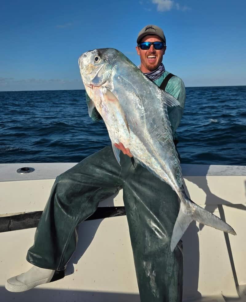 Angler holding an African pompano aboard All In Fishing Charters