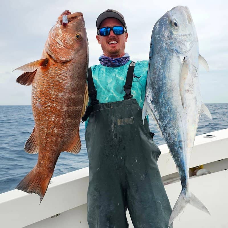 Angler showing two fish aboard All In Fishing Charters