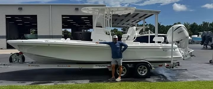 Angler standing beside a trailered center-console fishing boat at a boat shop