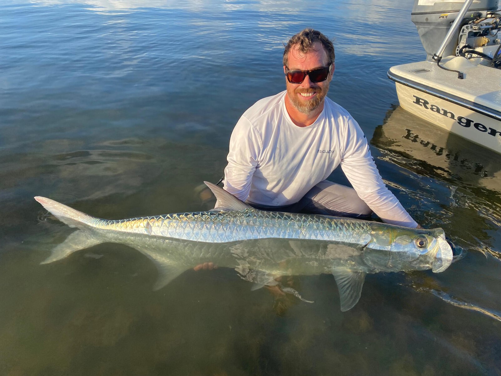 Angler standing in shallow water with a tarpon at Plantation Island Adventures
