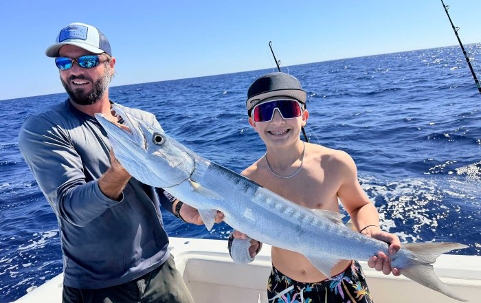 Anglers holding a barracuda with Fishy Business Charters