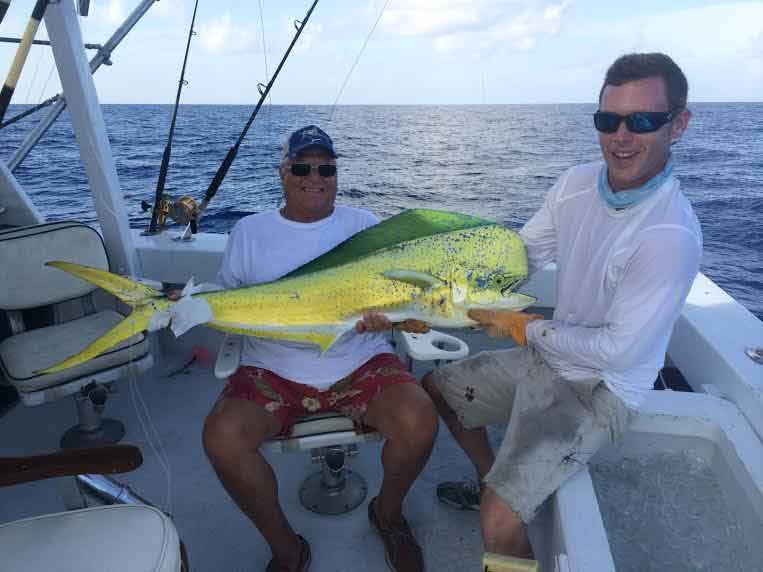 Anglers holding a mahi mahi on deck with Captain Moe’s Lucky Fleet