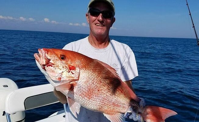Bay View Charters angler holding a large red fish beside the boat rail