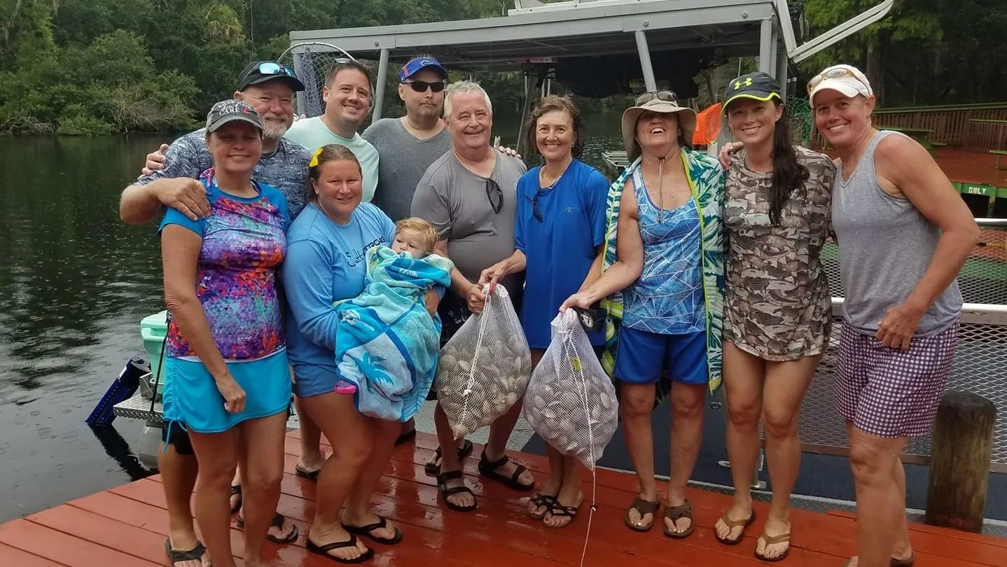 BWC Charters group holding bags of scallops at the dock