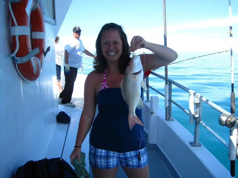 Captain Tony's Fishing Adventures angler displaying her catch beside the boat deck