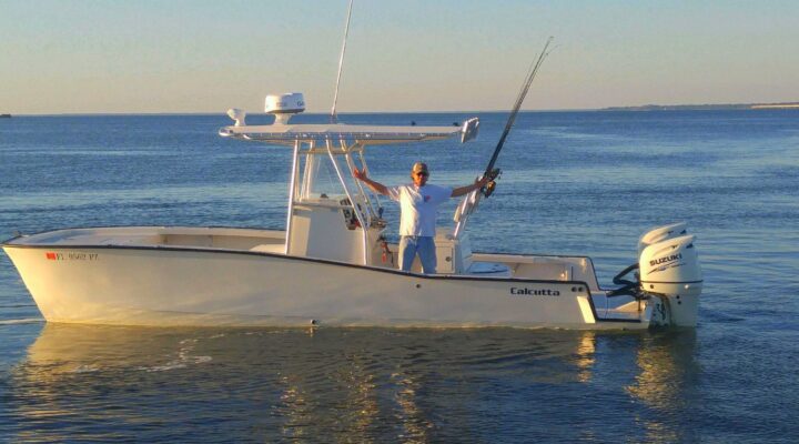 Center-console fishing boat with an angler standing beneath the T-top