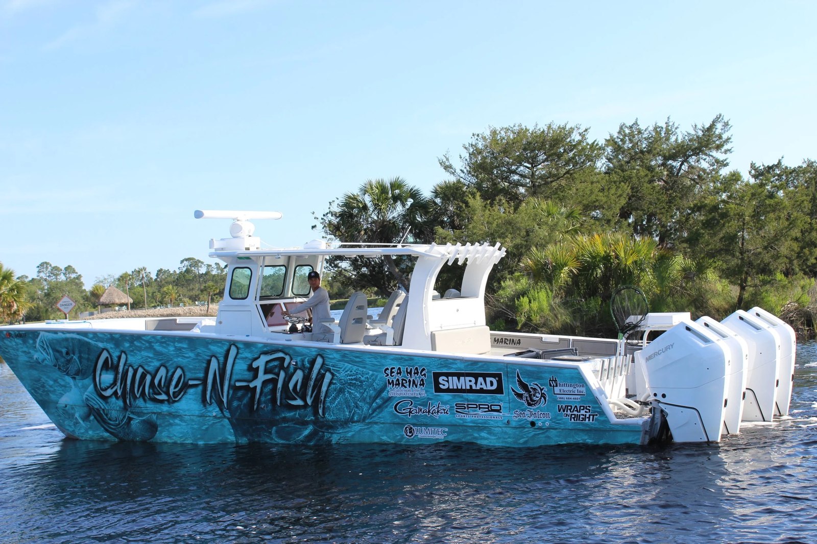 Chase-N-Fish center-console boat with multiple outboards beside a dock