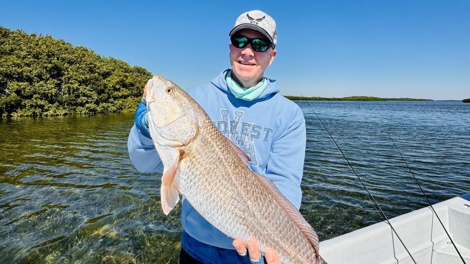 Crystal River Charter angler holding a redfish beside mangroves