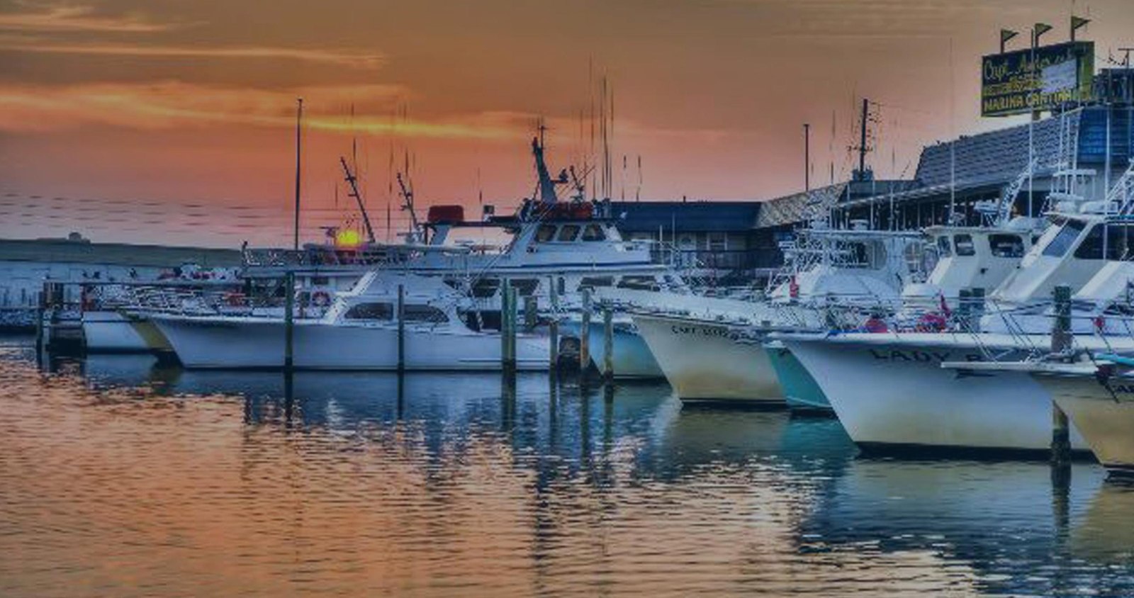 Fishing boats moored at Captain Anderson’s Marina under a sunset sky