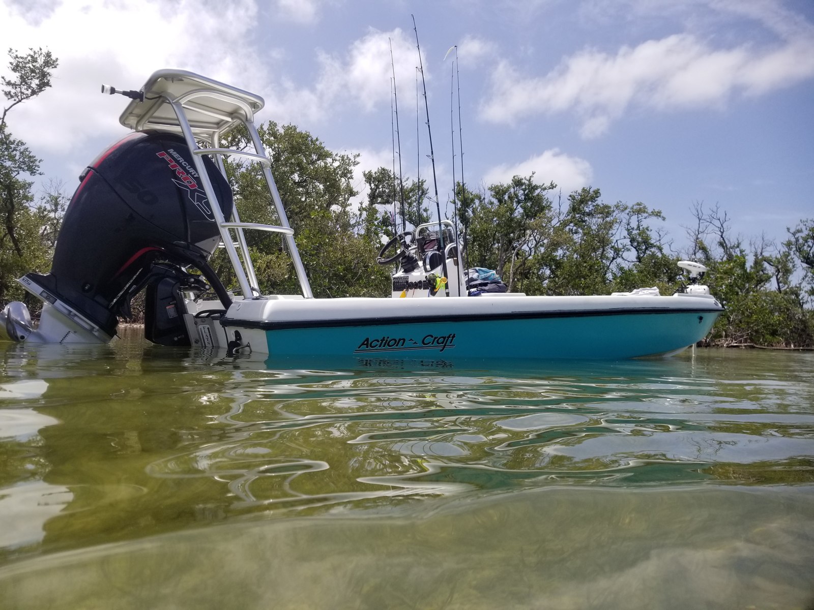 Flats skiff beside mangroves with Slightly Tighter Fishing