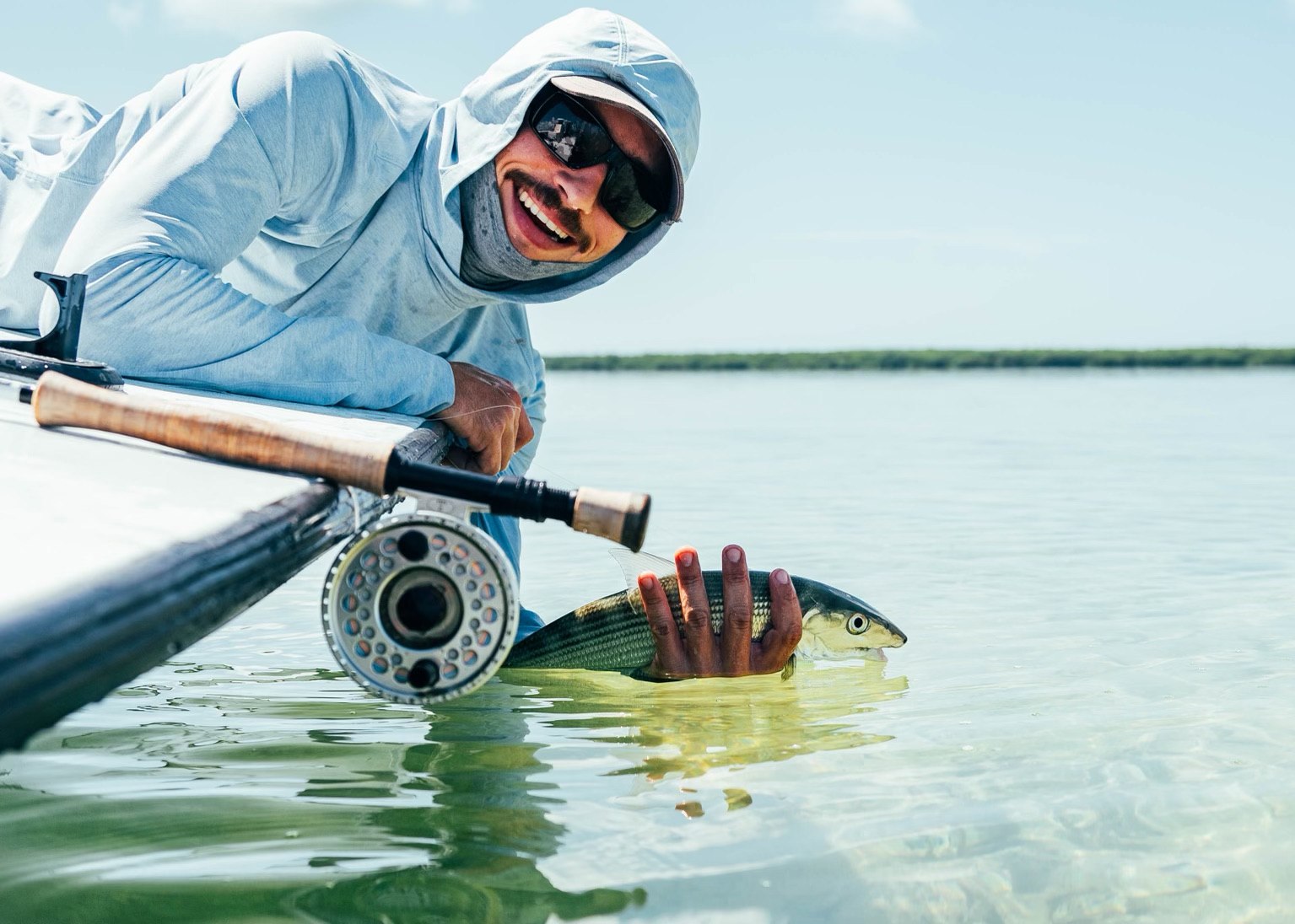 Fly angler holding a bonefish in the water with Dinsmore Fishing Charters