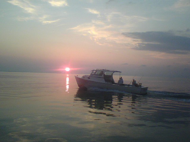 Gasparilla Outfitters fishing boat on calm water at sunset