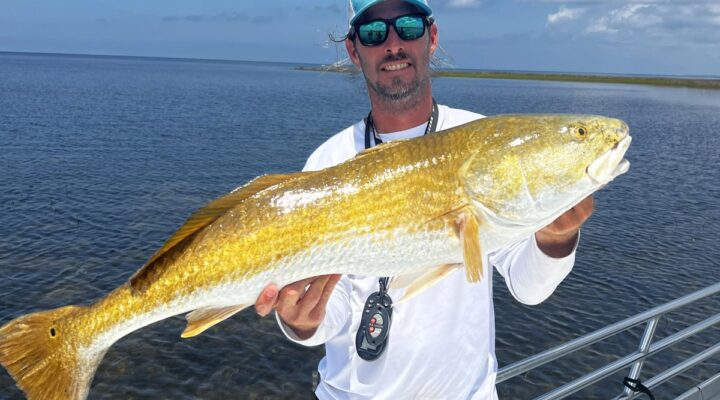 Hatch Snatch angler holding a golden-colored fish aboard a boat