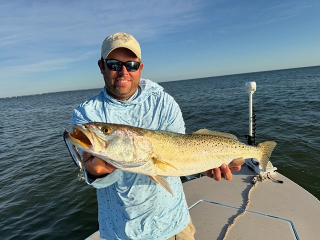 Helms Fishing angler holding a spotted fish beside the boat rail