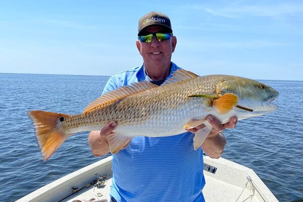 John’s Guide Service guest holding a large fish across the bow