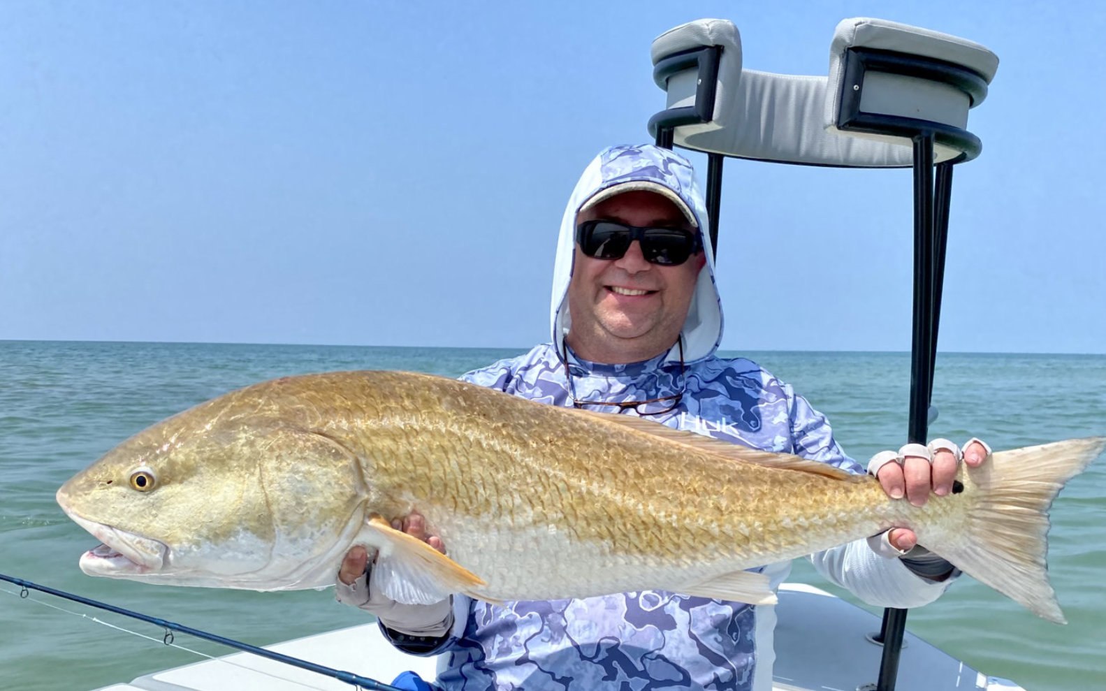 Robinson Brothers guest holding a redfish beside a skiff’s poling platform