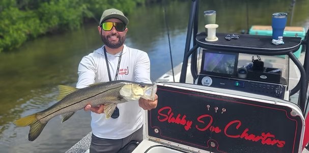 Slobby Joe Charters captain holding a snook beside the boat console