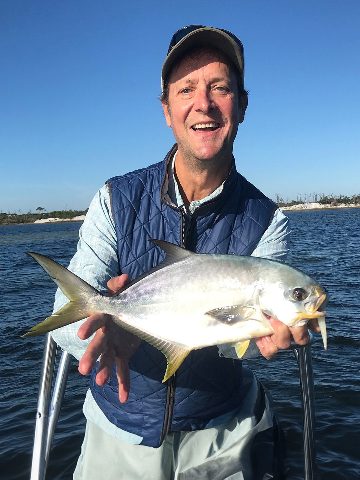 Smiling angler holding a silver fish on a Helms Fishing trip