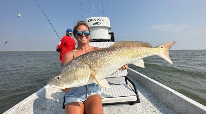 Southern Salt Charters guest holding a large redfish aboard a boat