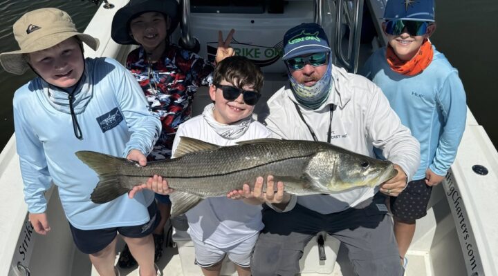 Strike One Fishing Charters group holding a snook on the boat