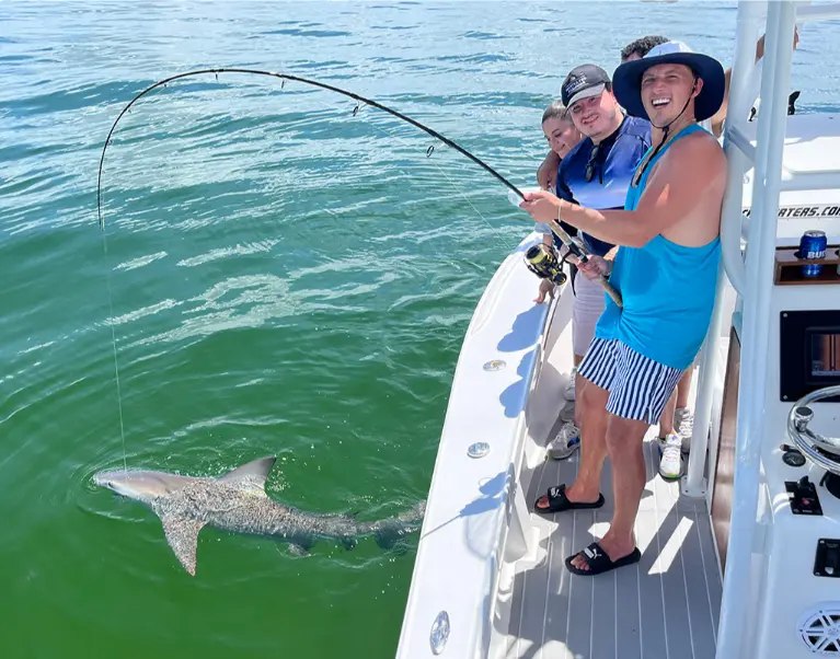 Treasure Island Fishing Charters guests with a shark beside the boat