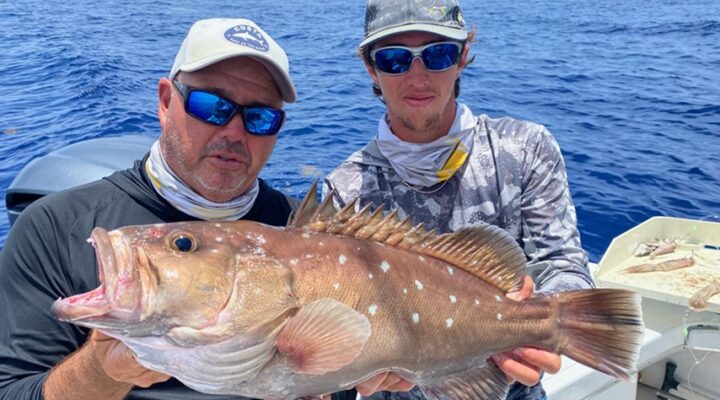Two anglers displaying a red grouper aboard Florida Boy Charters