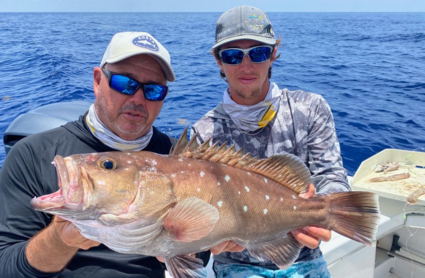 Two anglers displaying a red grouper aboard Florida Boy Charters