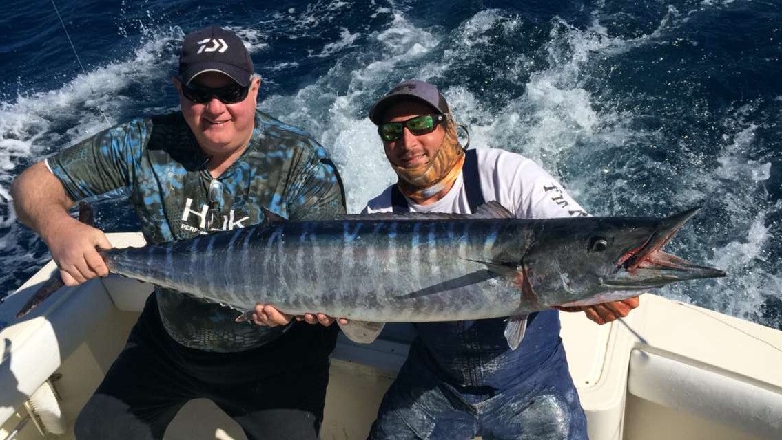 Two anglers displaying a wahoo aboard Key Largo Fishing Adventures