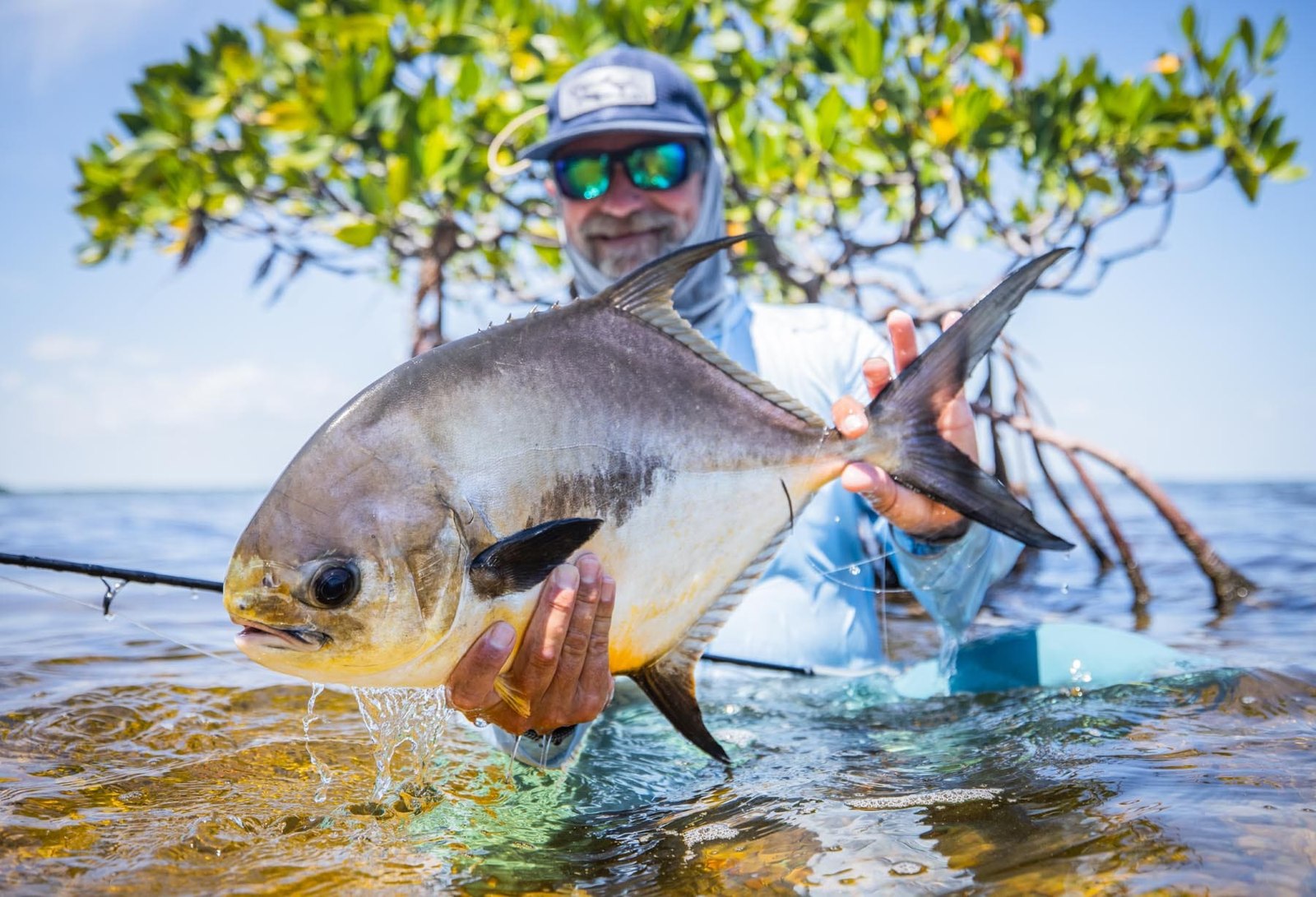 Wading angler holding a permit with Fly Water Florida Keys