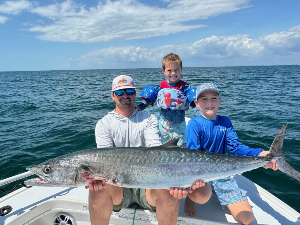 Wise Guy Fishing Charters family holding a king mackerel