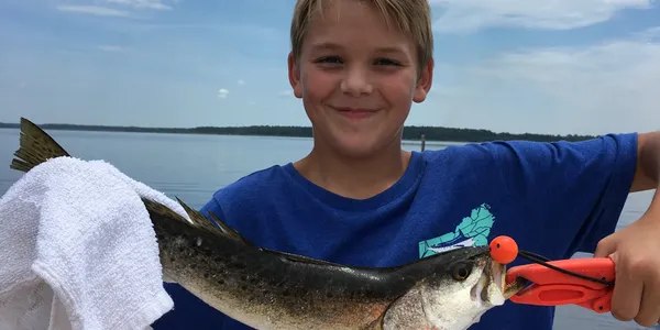 Young angler smiling with a fish on a Shallow Seas trip