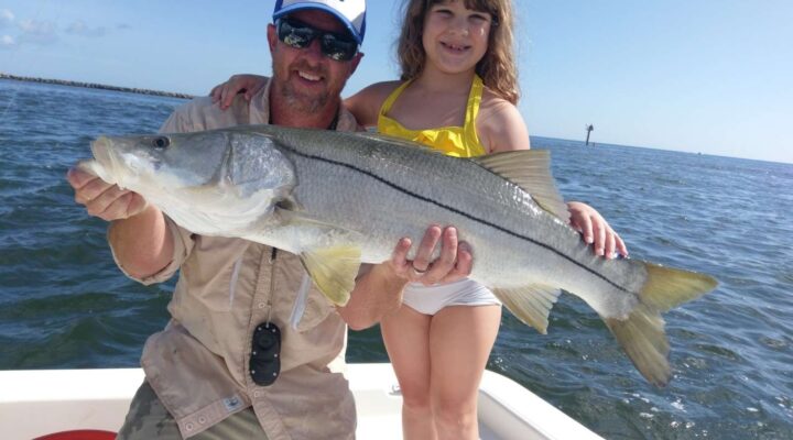 Adult and child holding a snook with Crossroads Charter Fishing