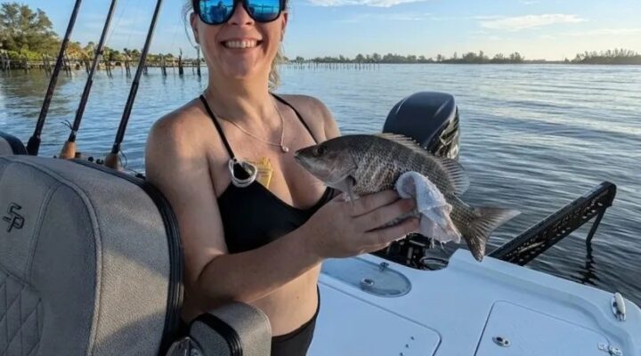 Against the Wind guest holding a spotted seatrout aboard a boat