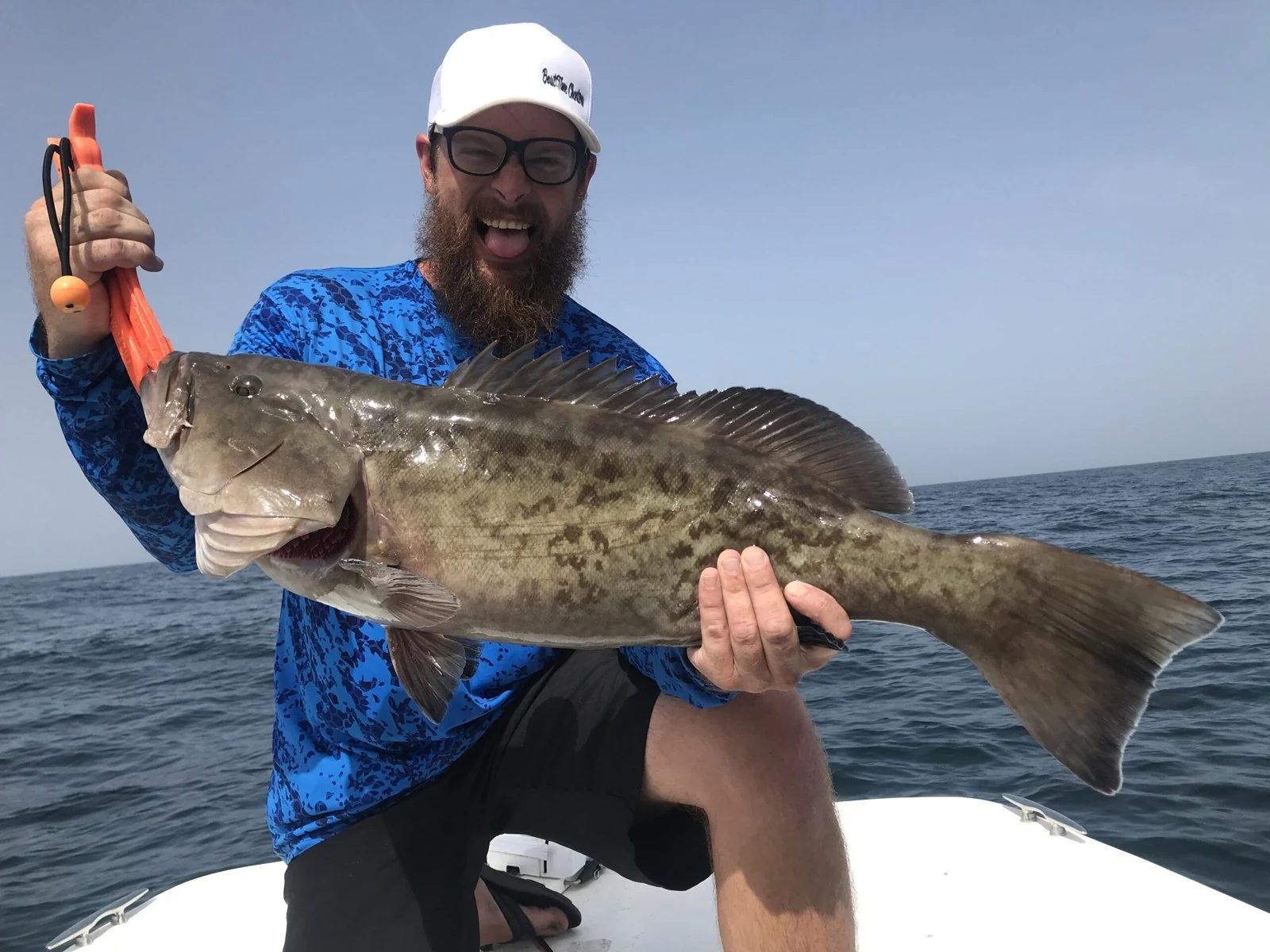 An angler holds a grouper aboard a Bout Time fishing charter