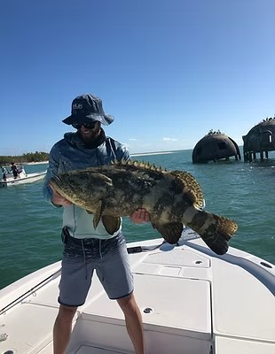 Angler displaying a grouper with Uncharted Adventures