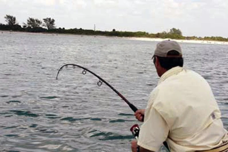 Angler fighting a fish from a shallow-water boat
