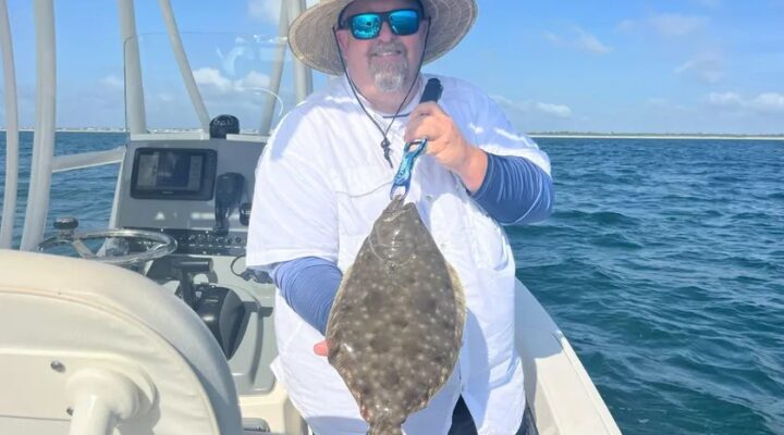 Angler holding a flounder aboard Back At It Fishing Charters