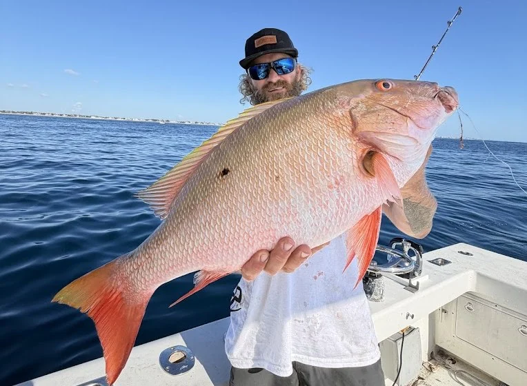Angler holding a large snapper aboard Strike Mission
