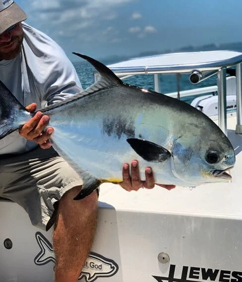 Angler holding a permit aboard a Hot Water Fishing skiff