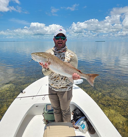 Angler holding a snook aboard The Twisted Fly